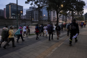 Grupo de pessoas em situação de vulnerabilidade caminhando por área urbana durante o entardecer, ilustrando os impactos das drogas sintéticas e da dependência química no Brasil.